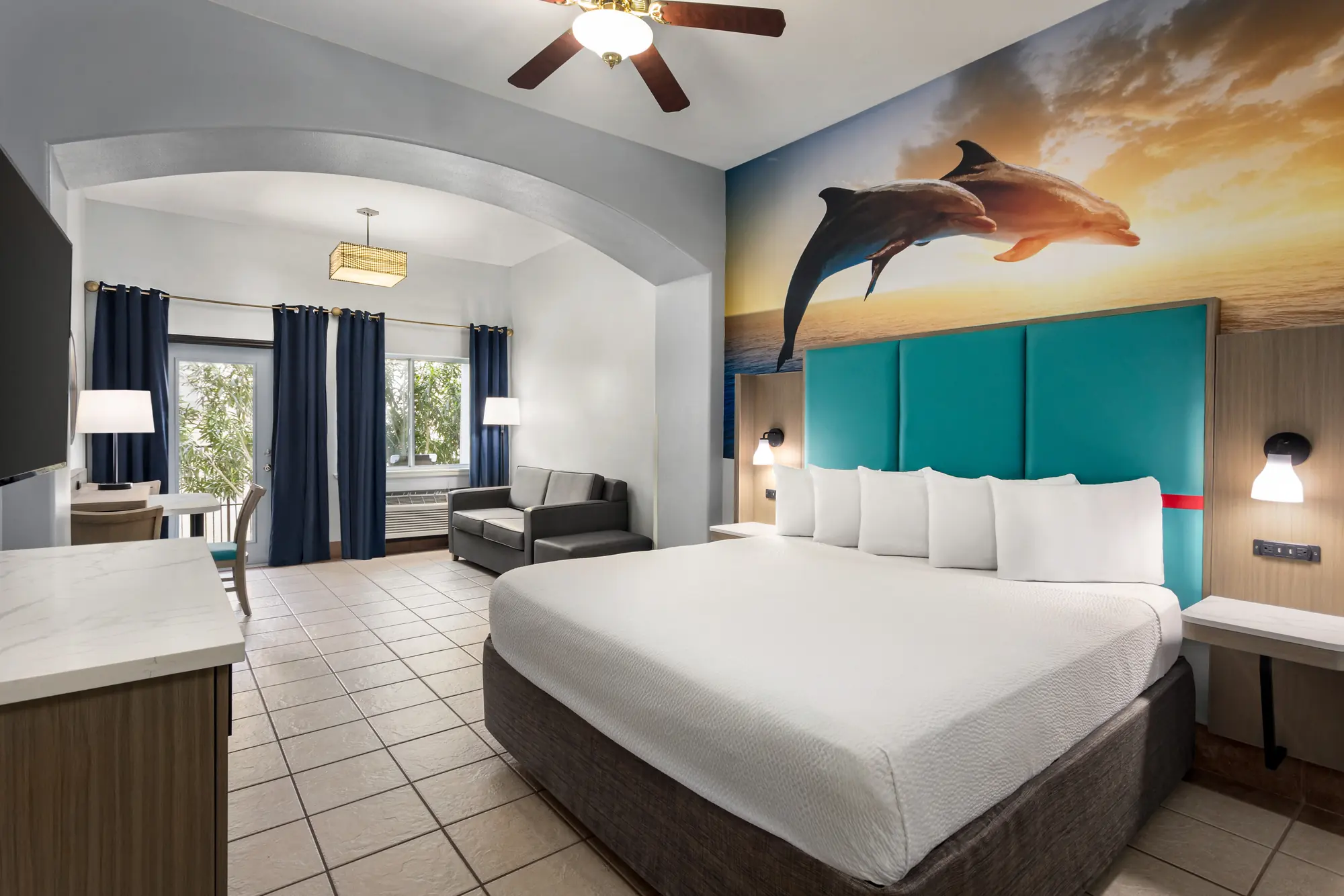 King bed under a sunset dolphin mural