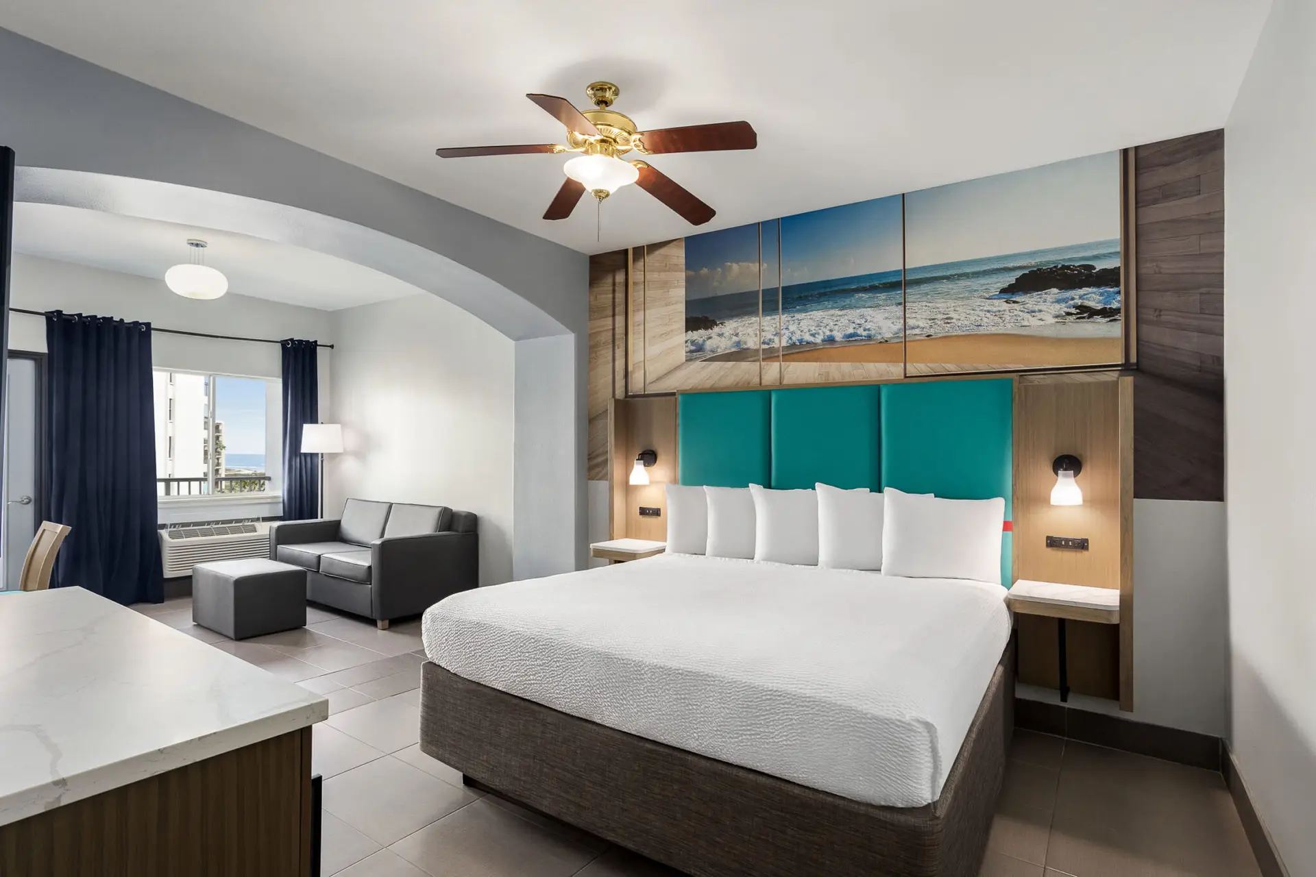 King bed with a teal headboard under a beach mural