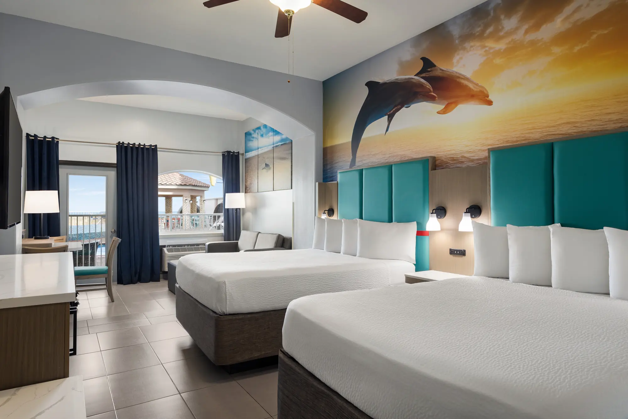 Two queen beds under a dolphin mural, with the window facing the pool